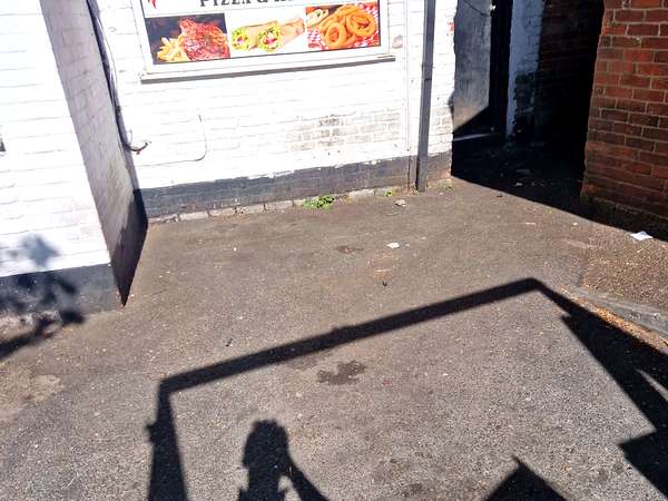 Cleared rear yard behind a high street takeaway after a commercial clearance