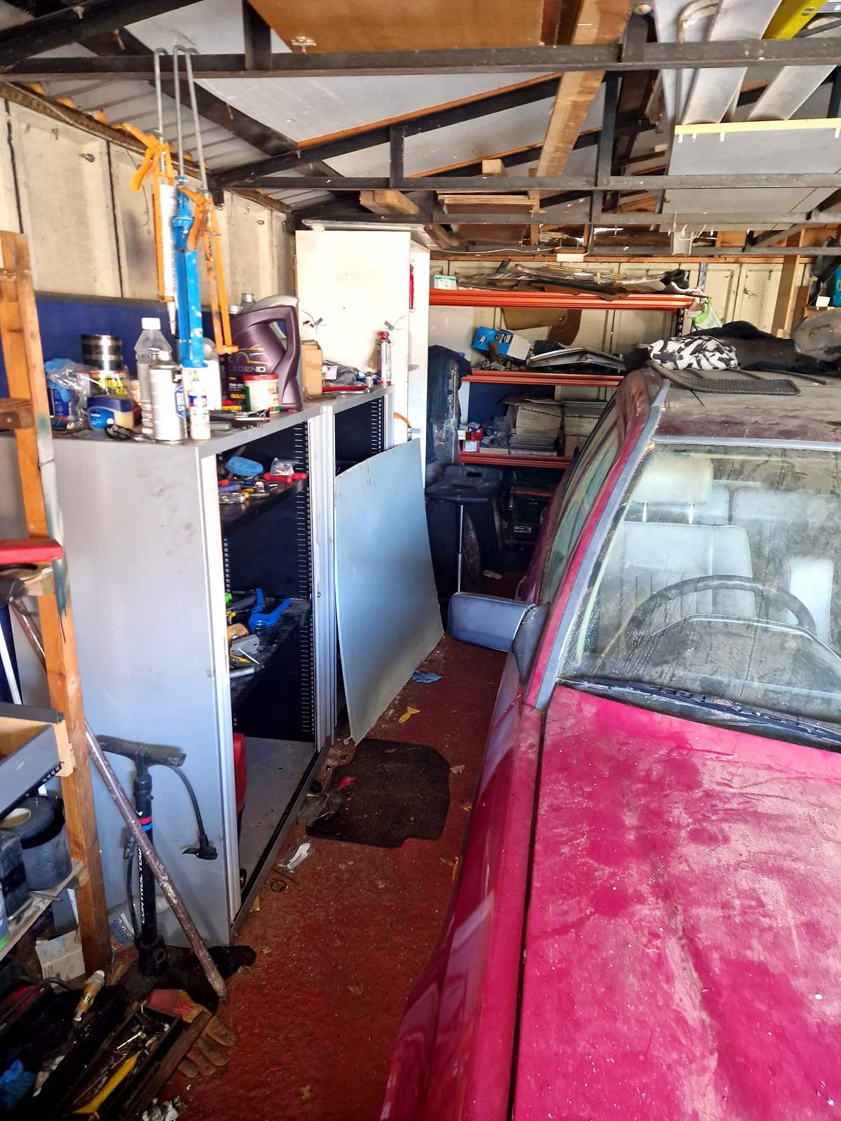Packed double garage with a car inside, shelving and decades of stored belongings