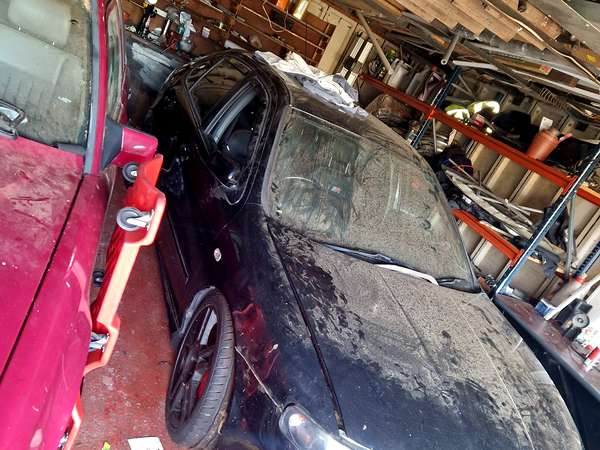 Two cars stored in a cluttered garage awaiting clearance