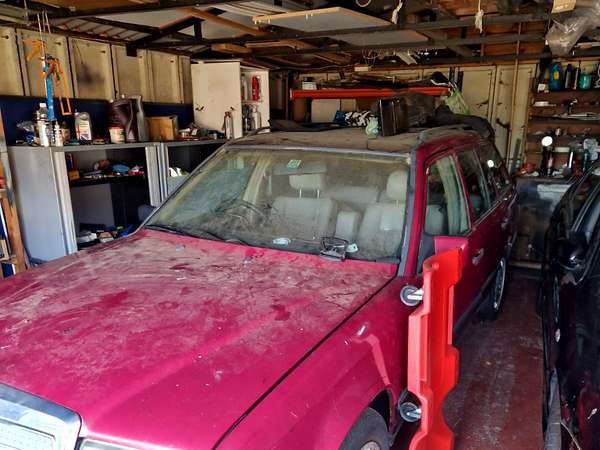 A dust covered classic Mercedes parked inside a garage due for clearance