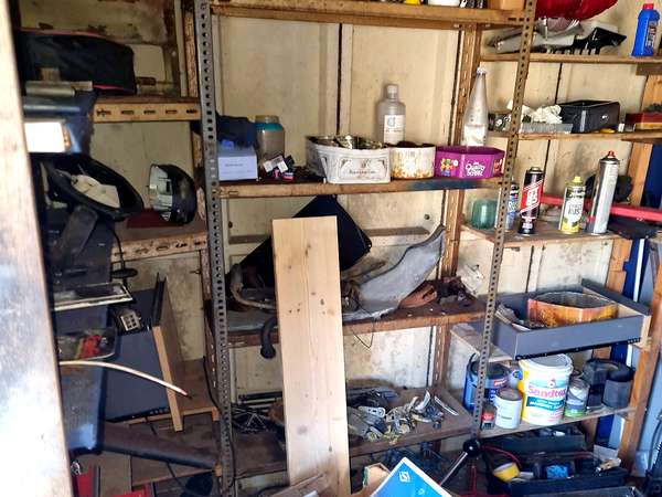 Shelves of tools, paint tins and workshop clutter in a garage clearance