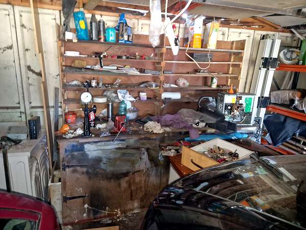 Cluttered workbench and shelving in a garage before clearance