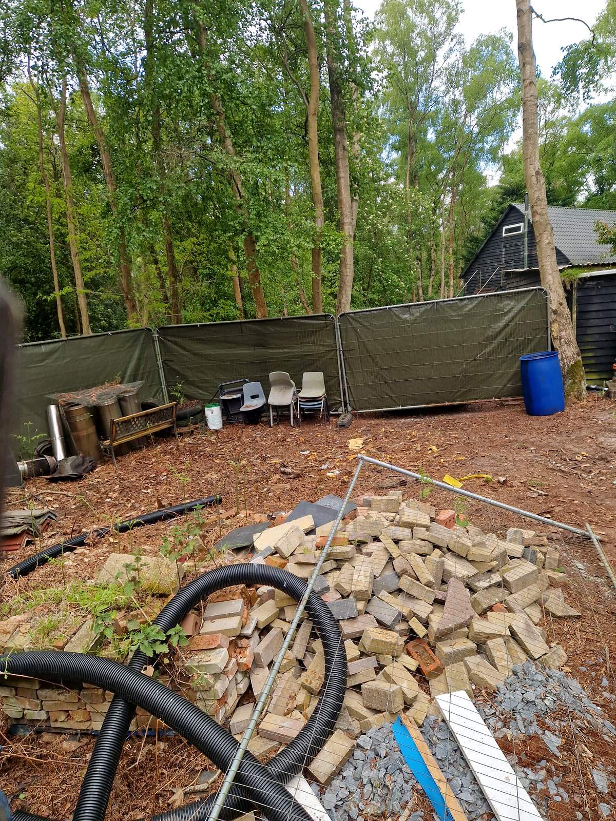 The same garden cleared down to bare ground with rubble stacked for removal