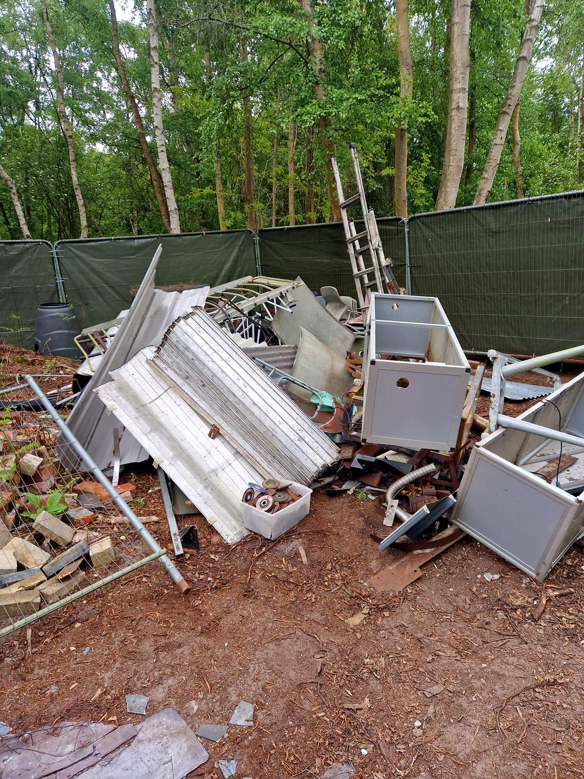 Pile of scrap metal, cupboards and building waste in a garden before clearance