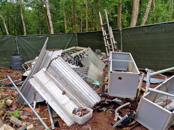 Pile of scrap metal, cupboards and building waste in a garden before clearance