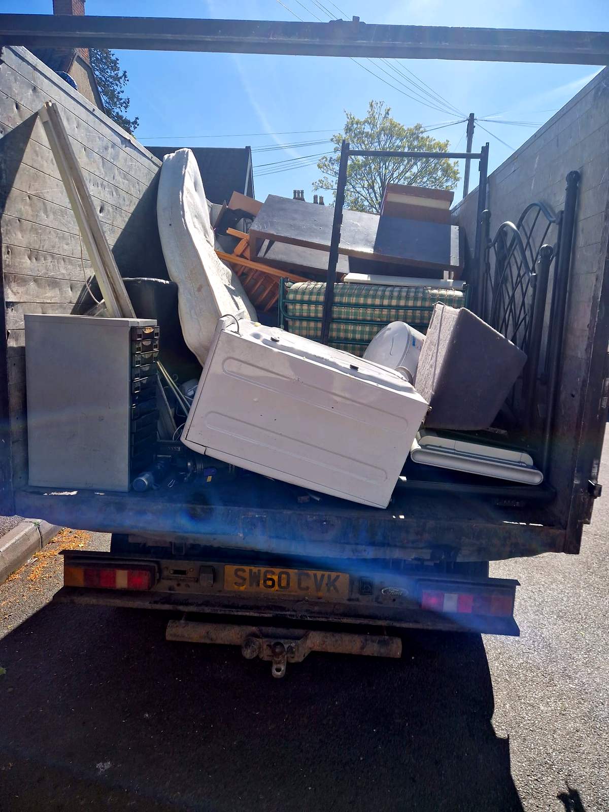 Tipper loaded with old furniture, mattresses and bed frames