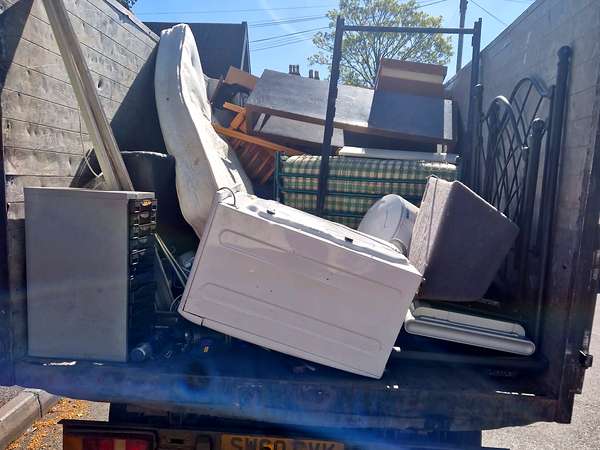 Tipper loaded with old furniture, mattresses and bed frames