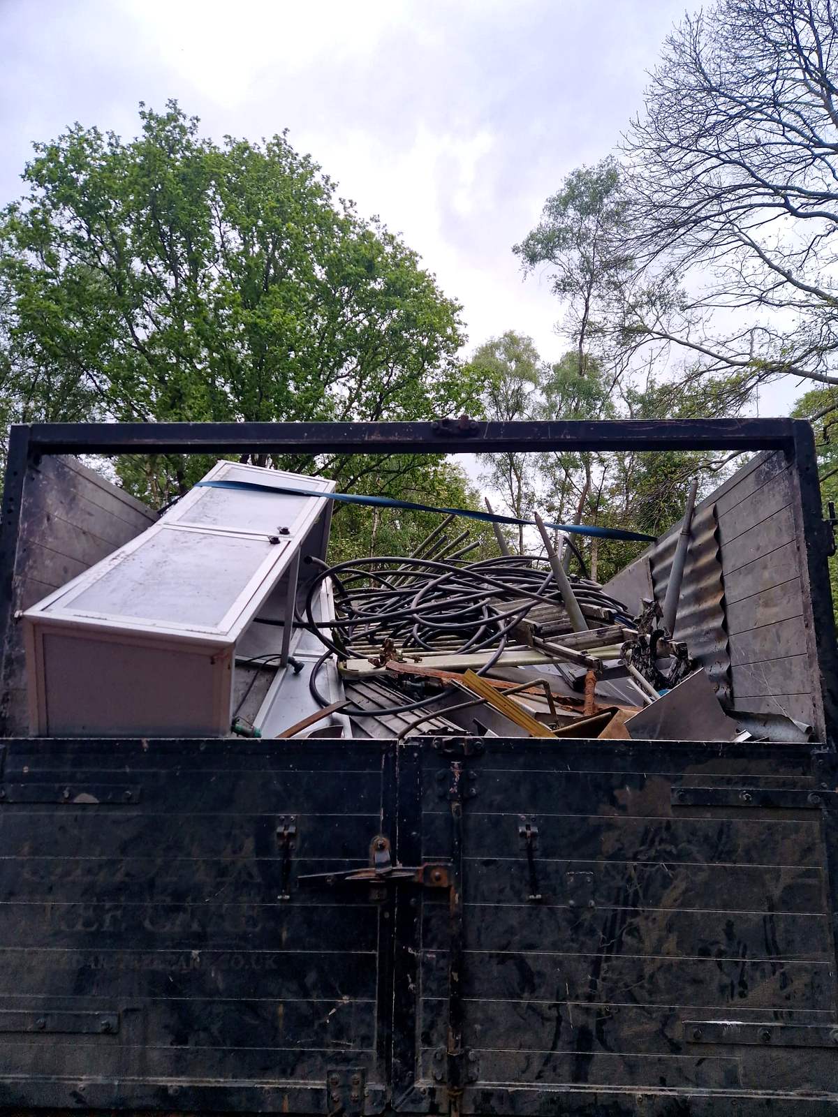 Tipper body loaded with scrap metal and an old freezer