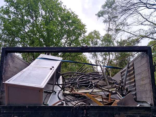 Tipper body loaded with scrap metal and an old freezer