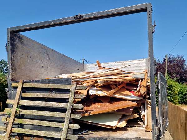 Tipper truck loaded with broken timber and old fencing after a house clearance
